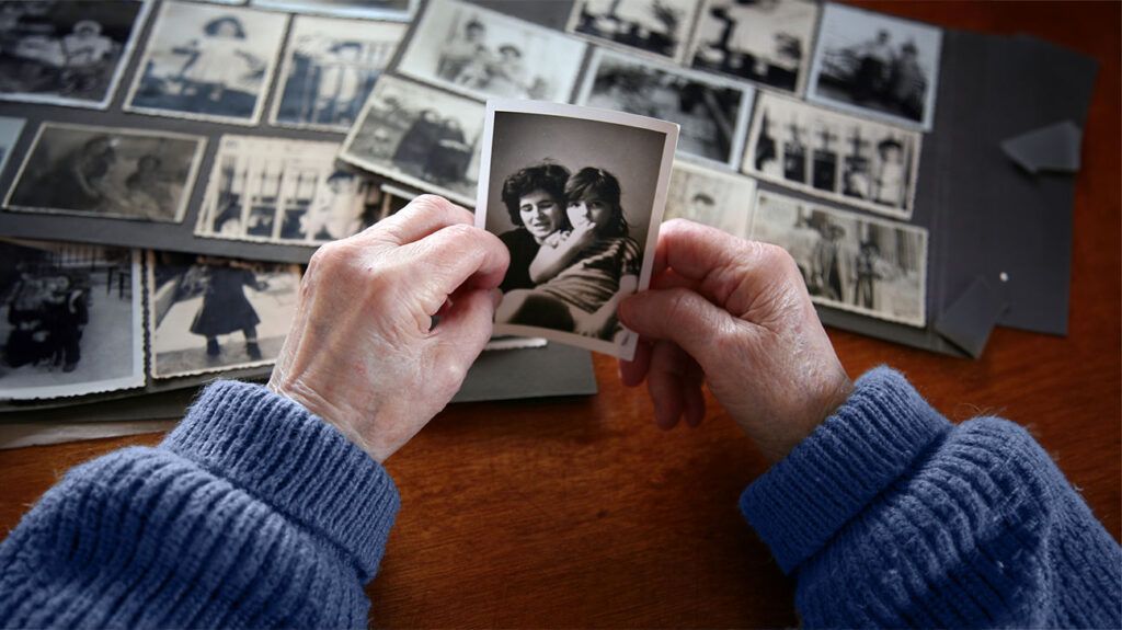 the hands of an old man holding a black and white photo of a mother and her daughter